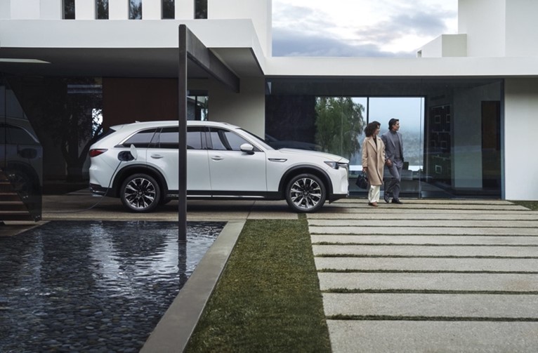 Guía de compra de vehículos eléctricos  –  Mazda CX-90 PHEV estacionado cerca de una piscina