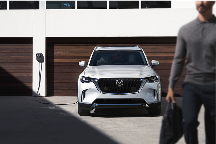 ¿Cuánto tiempo tarda en cargarse un auto eléctrico?  –  Un Mazda CX-90 PHEV cargándose fuera de un garaje