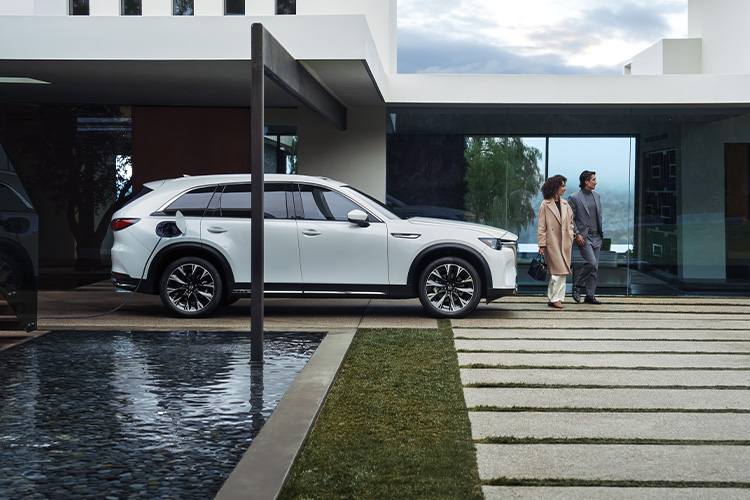 Guía de compra de vehículos eléctricos  –  Mazda CX-90 PHEV estacionado cerca de una piscina