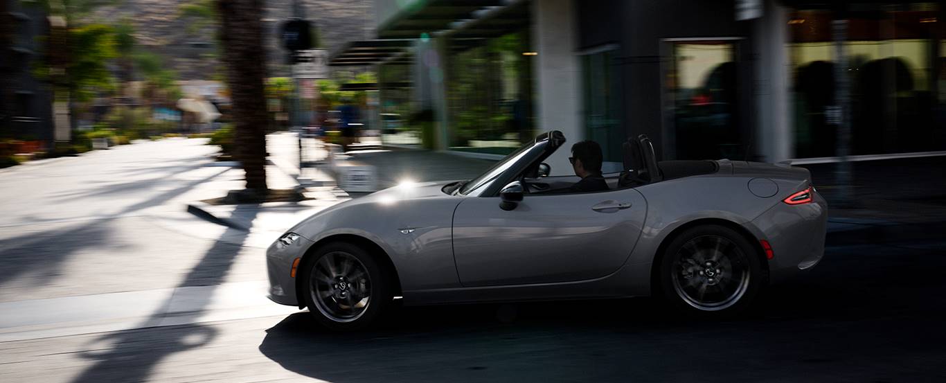  2024 Mazda MX-5 Miata driving through city. 